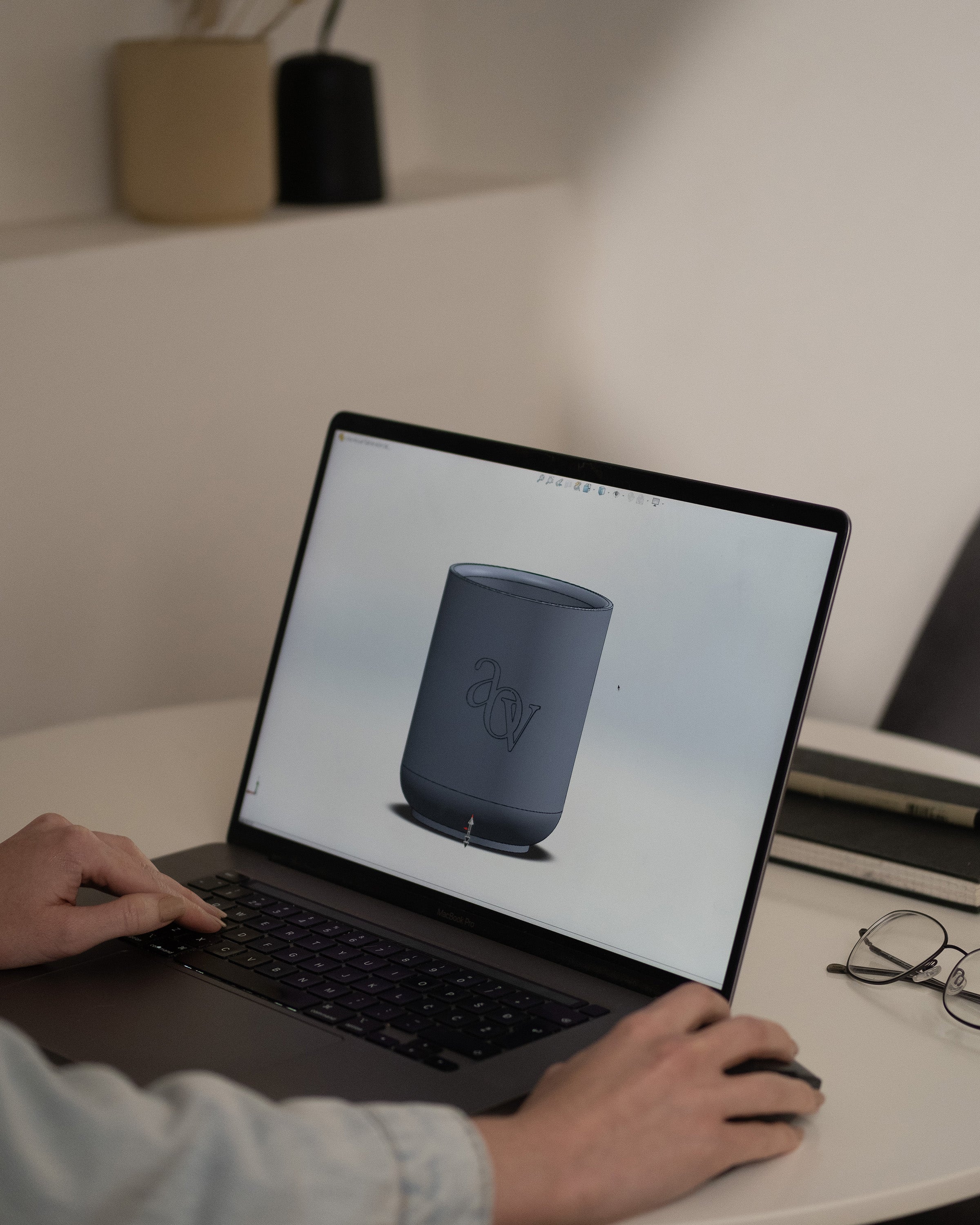 Person designing a custom 3D candle vessel with a logo on a laptop before creating a silicone mold