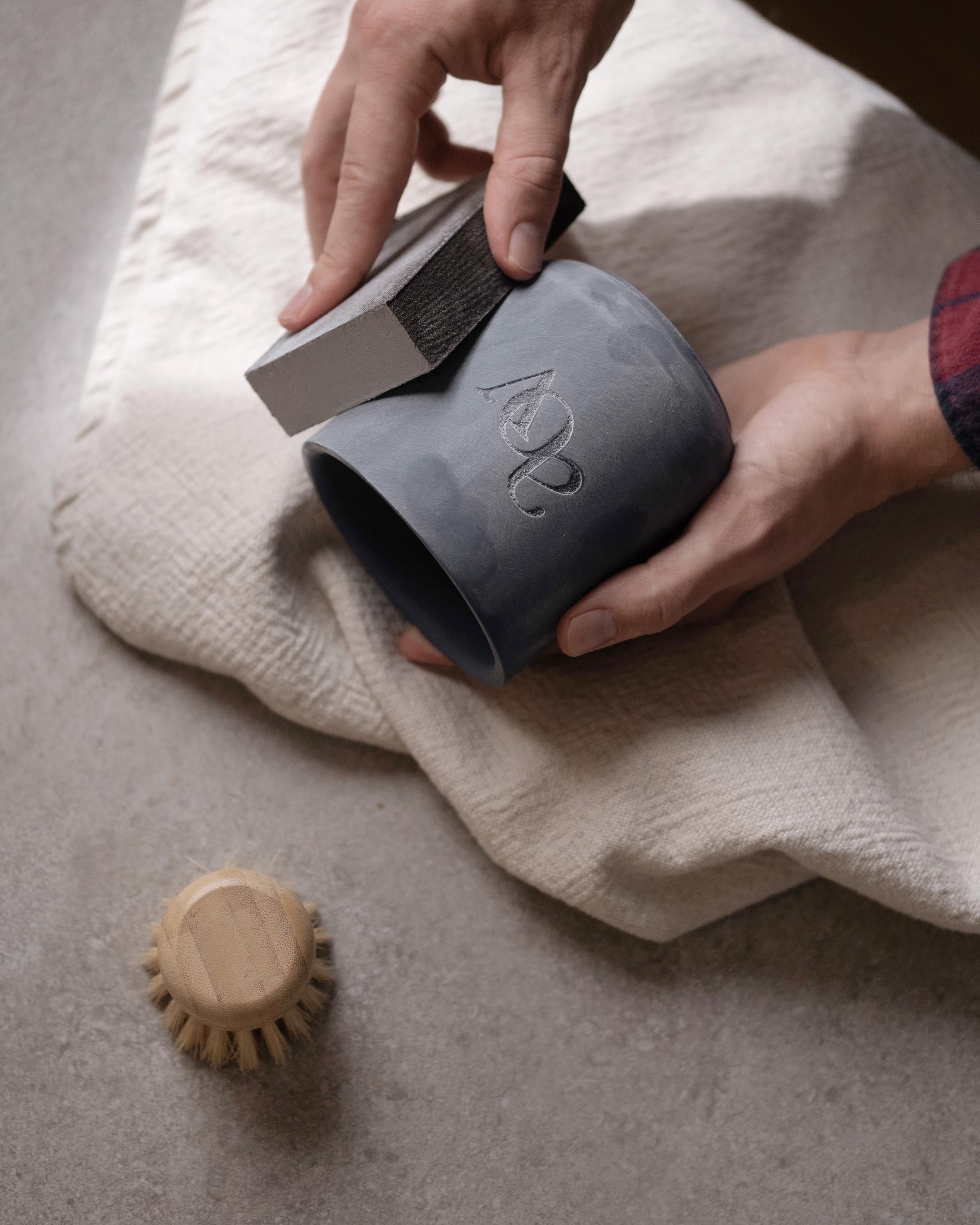Person hand sanding a 3D printed master jar with a custom embossed logo to prepare it for silicone mold production.