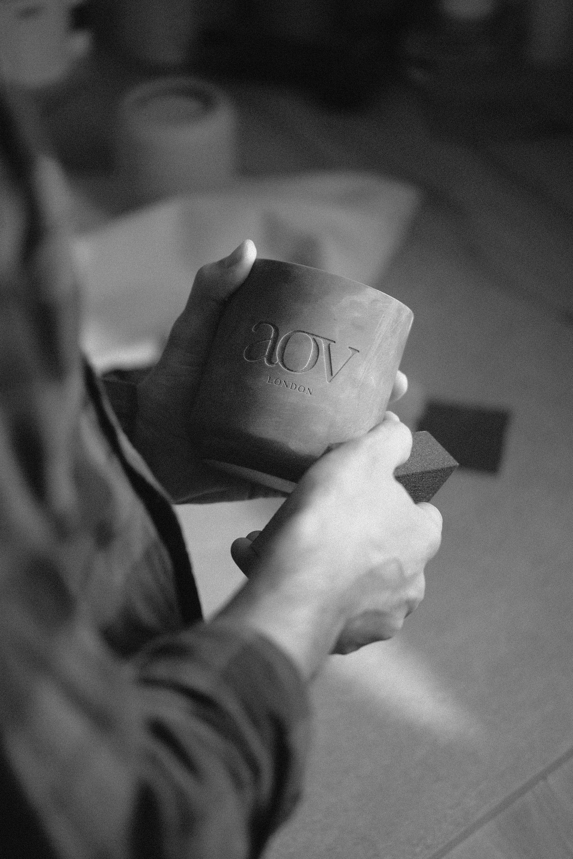 Person sanding a 3D printed master jar with a custom logo before silicone mold making.
